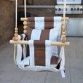 Load image into Gallery viewer, Brown and white striped swing chair hanging outdoors on a patio.