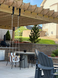 Load image into Gallery viewer, Outdoor patio area with wooden pergola, chairs, and a grill on a sunny day.