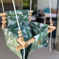 Load image into Gallery viewer, Outdoor baby swing with vibrant green palm pattern, high back seat shown in outdoor patio set up
