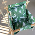 Load image into Gallery viewer, Top view bold tropical leaf print baby swing hanging on front porch shown with 2 pillows