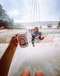 Load image into Gallery viewer, baby using french gray buffalo check baby swing while mama enjoys free hands and a cup of coffee