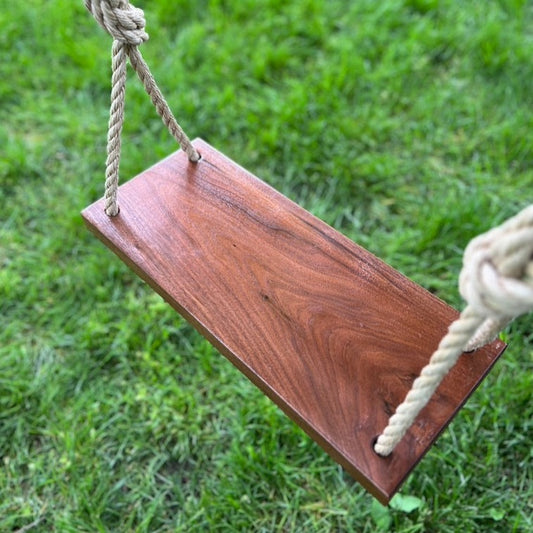 close up on walnut wood bench swing shown with natural brown rope