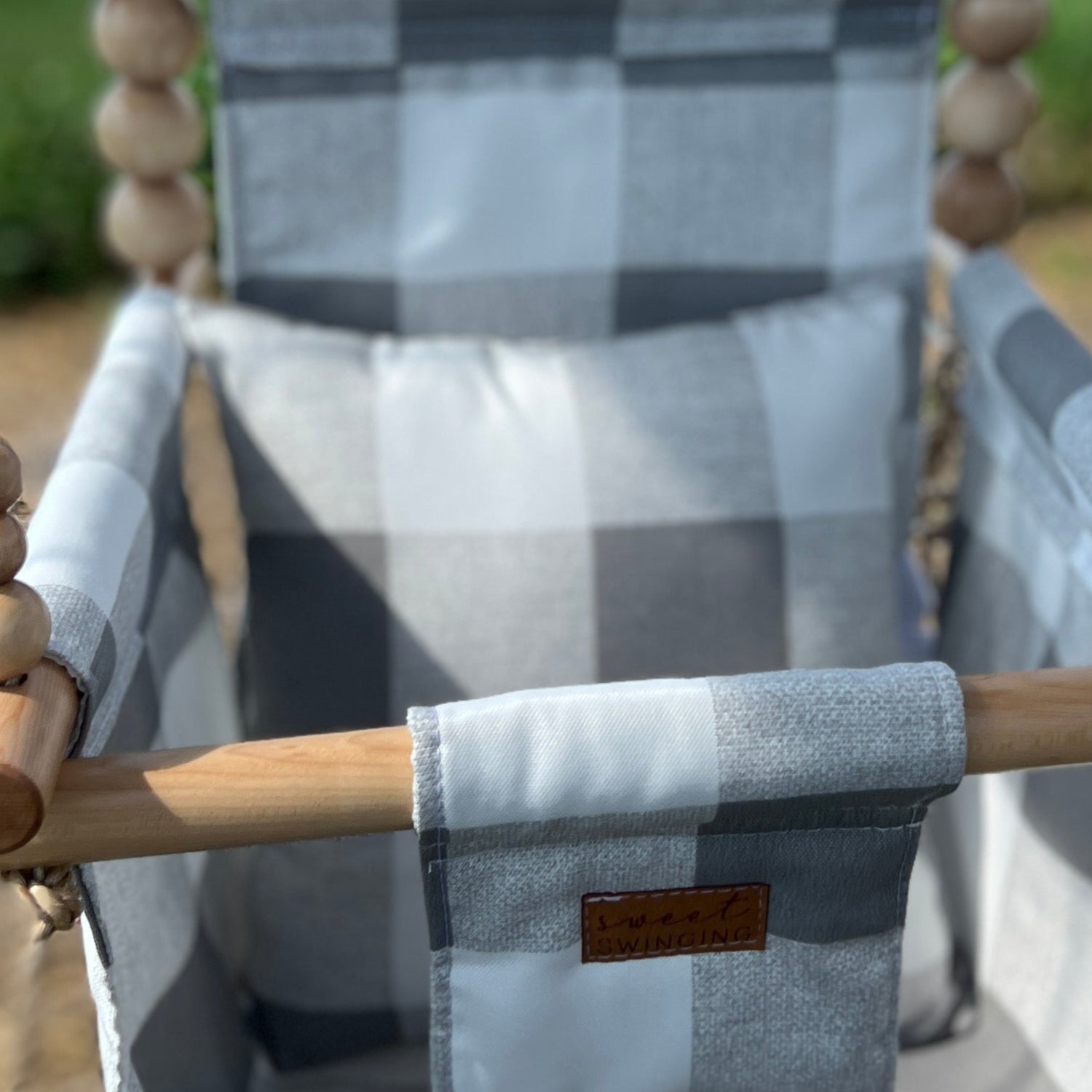 Wooden swing with a checkered blanket in an outdoor setting