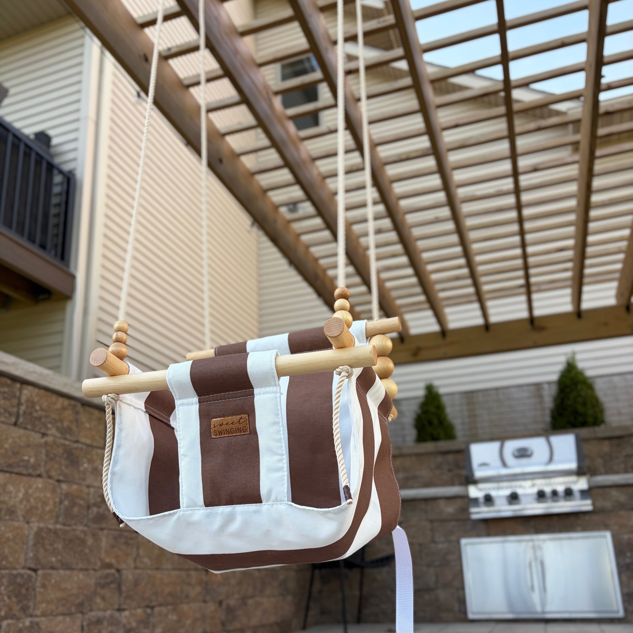 Brown and white striped swing hanging outdoors on a patio