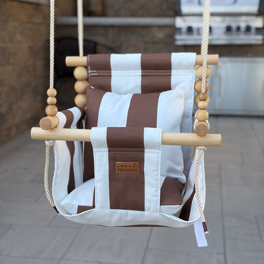 Brown and white striped swing chair hanging outdoors on a patio.