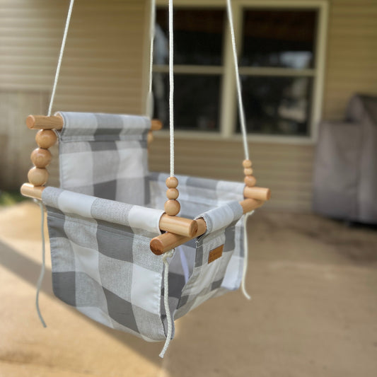 Side view of weather-resistant baby swing in gray buffalo check fabric